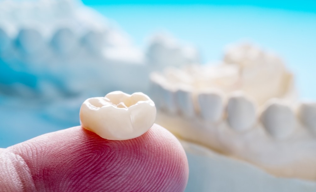 Close up of person holding a dental crown on their finger
