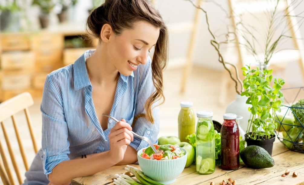 Woman sitting at wooden table eating a salad
