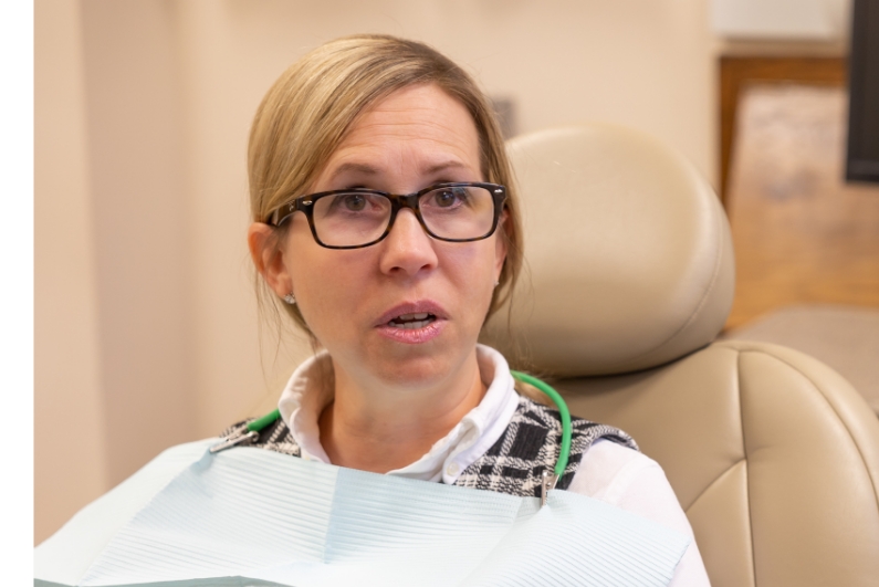 Woman in dental chair talking to emergency dentist in Ormond Beach