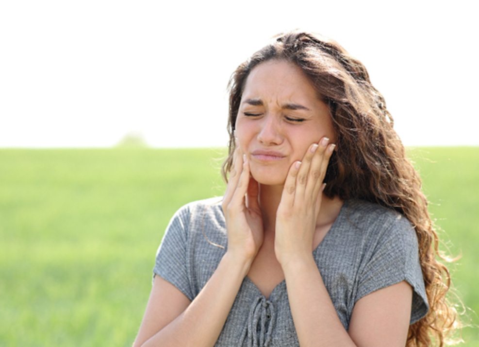 Woman in field with jaw pain from TMJ disorder in Ormond Beach, FL