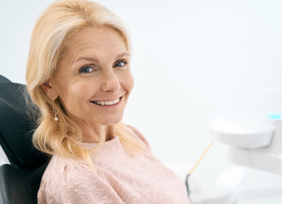Blonde woman smiling and sitting in dental chair