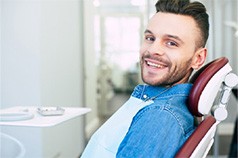 Male patient in dental chair looking to side and smiling