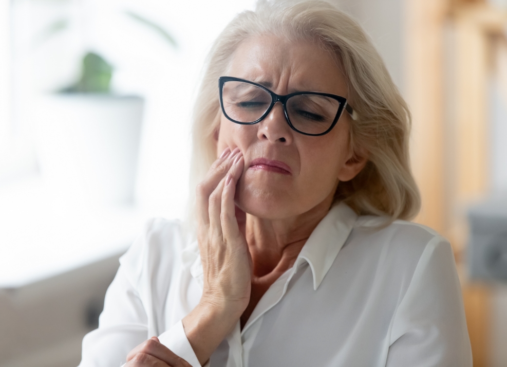 Senior woman holding her cheek in pain