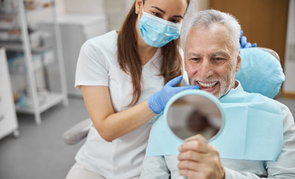 a dental patient checking their smile with a mirror