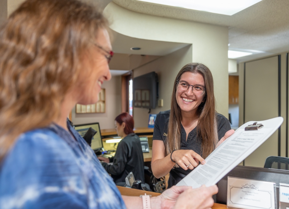 Dental team member showing a form on a clipboard to a dental patient