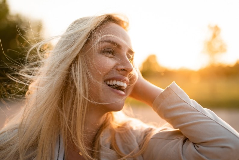 Blonde woman laughing outdoors on sunny day