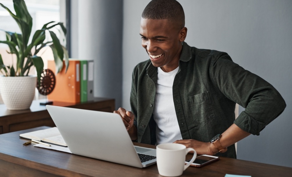 Man sitting at desk smiling at laptop