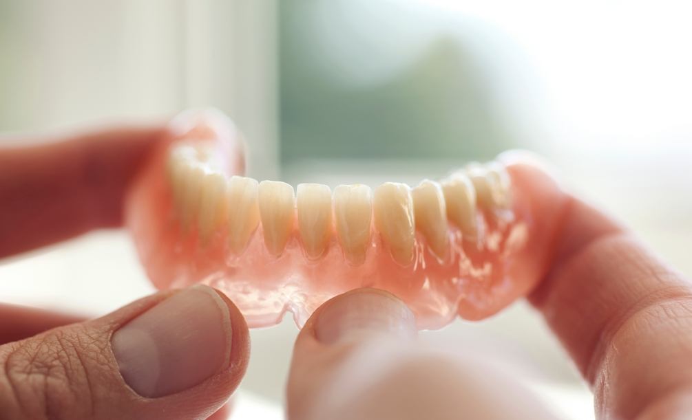 Close up of person holding a full denture in their hands