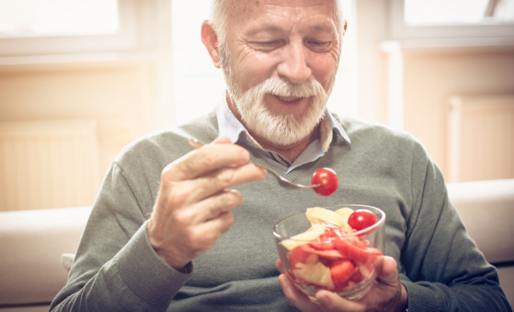Senior man eating a salad with cherry tomatoes
