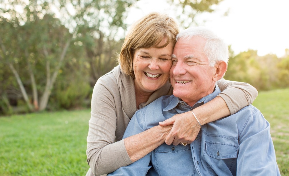 Senior man and woman holding each other in a grassy field