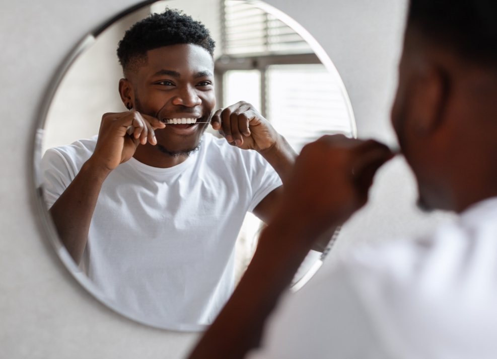 Young man smiling while flossing his teeth