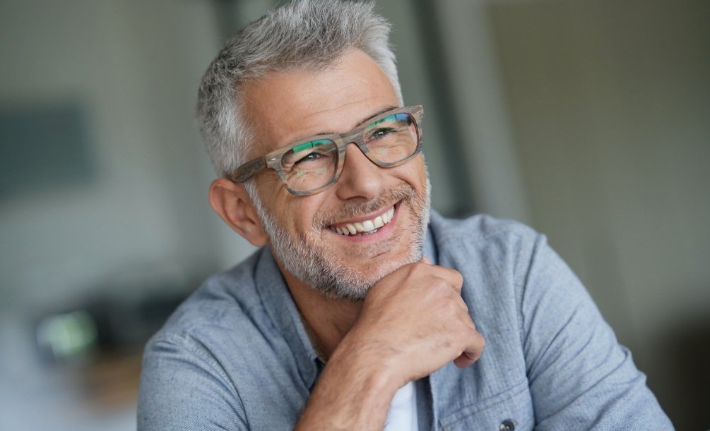 Smiling older man in glasses and denim shirt