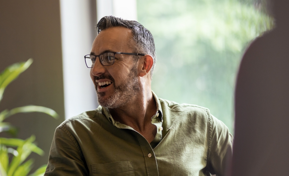 Smiling man in glasses and dark green button up shirt