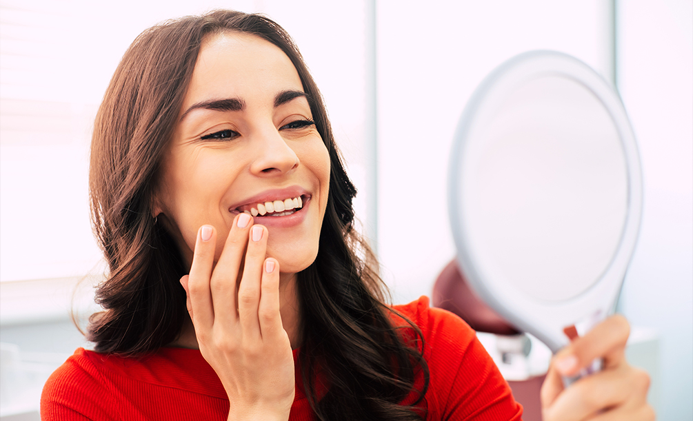 Young woman admiring her smile in a mirror