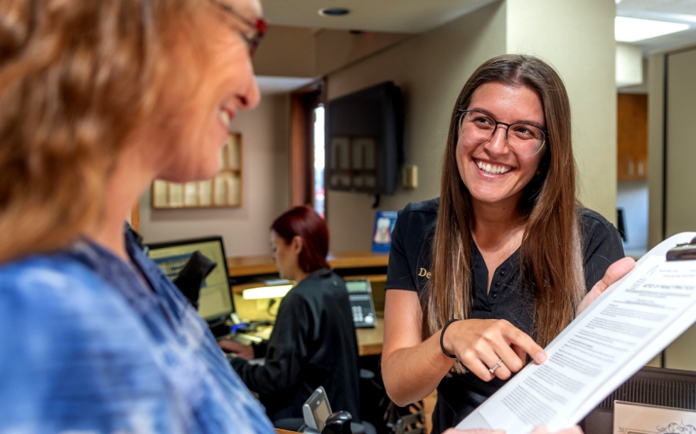 Ormond dental team member showing a dental patient where to sign on paper on clipboard