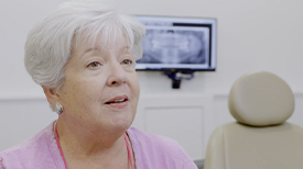 Senior woman in pink blouse sitting in dental exam room