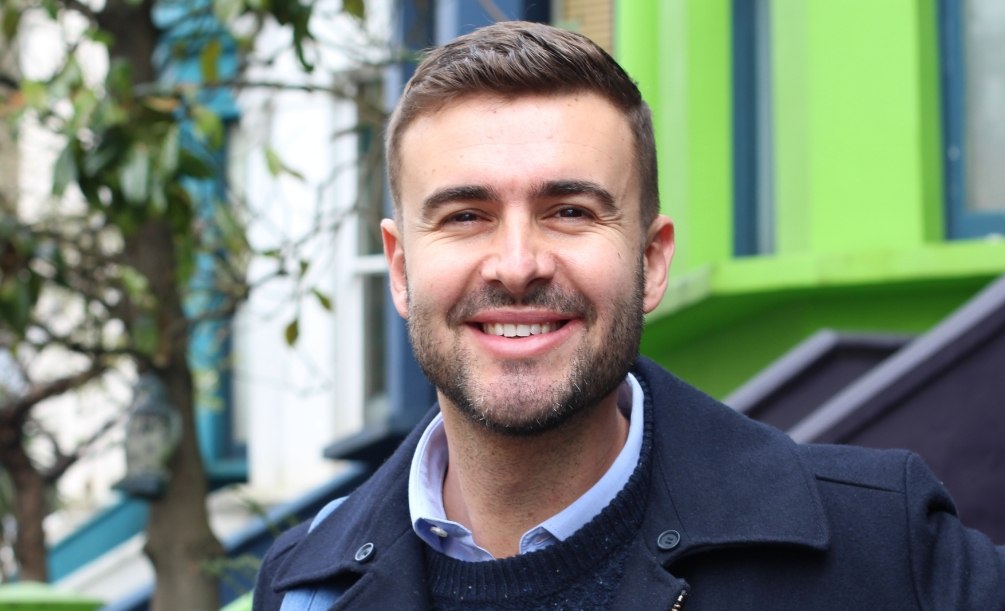 Man in navy blue peacoat standing on sidewalk