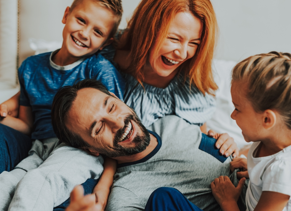 Family of four cuddling on couch and laughing together