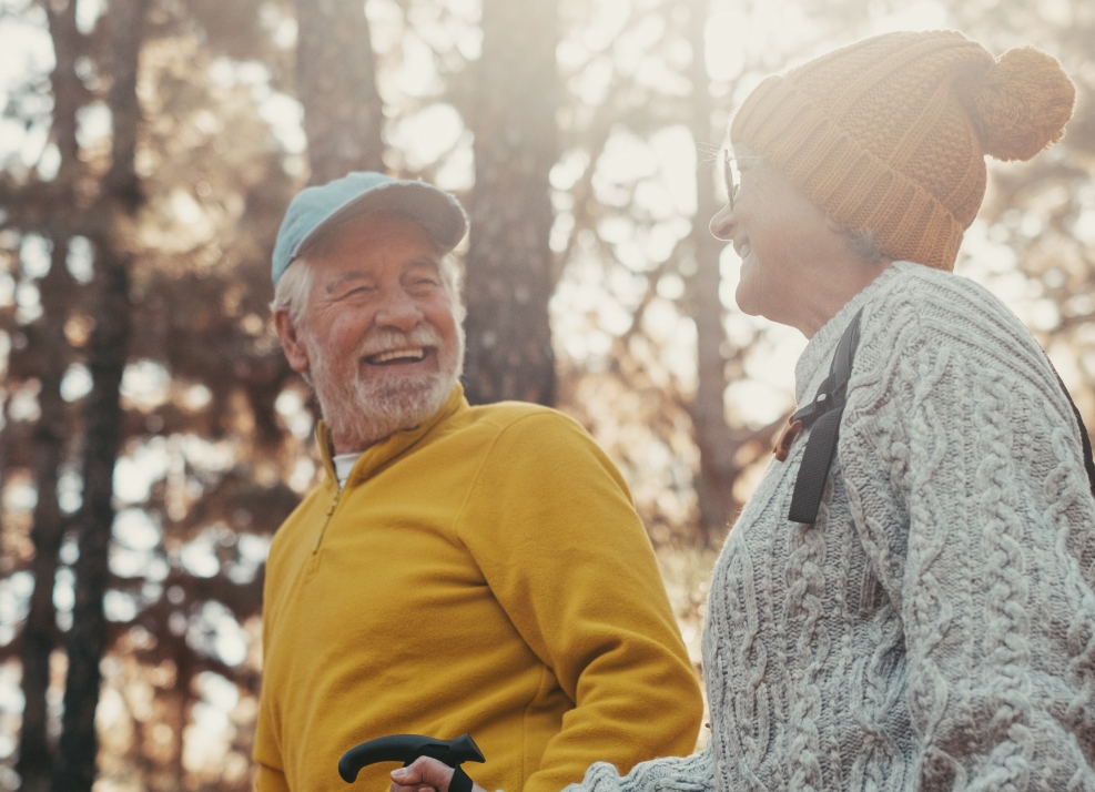 Happy senior man and woman walking through the woods together on sunny day