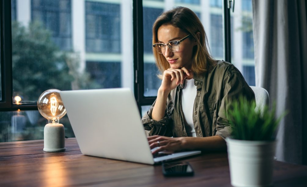 Woman sitting at table reading on her laptop