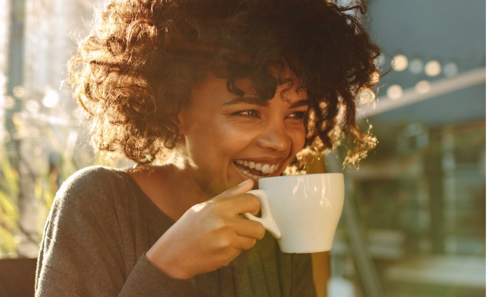 Laughing woman holding white coffee mug