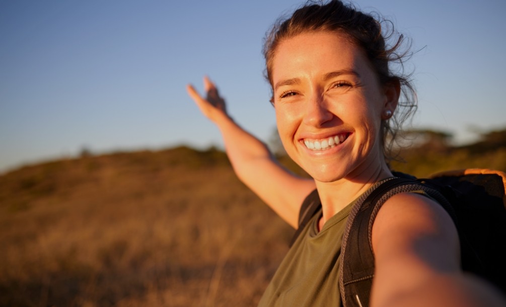 Selfie of young woman with field in background on sunny day