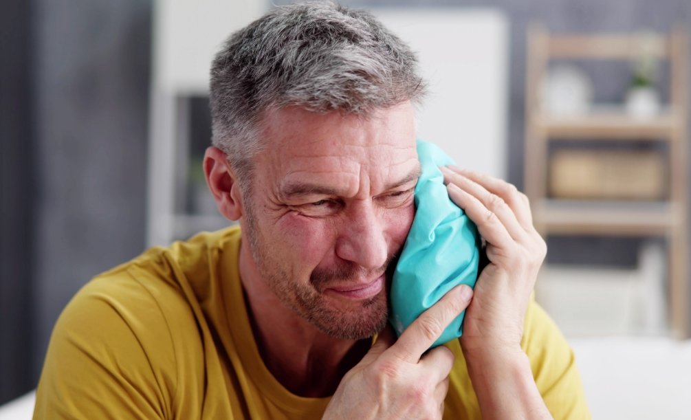Man holding a cold compress to his cheek