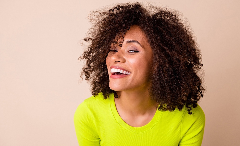 Woman in green sweater smiling with perfect teeth