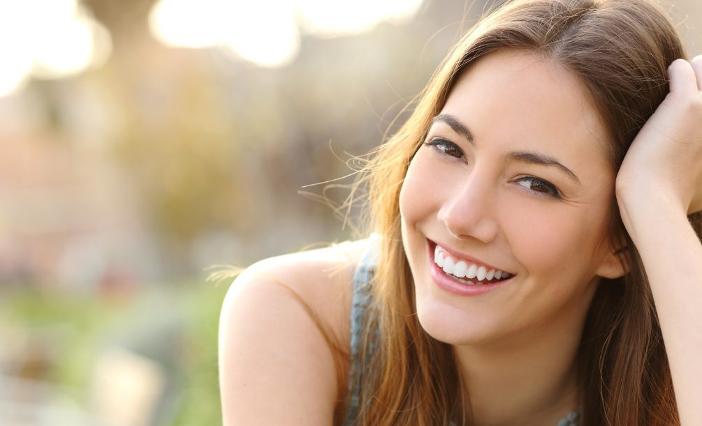 Young woman smiling outdoors on sunny day