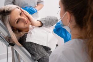Patient holding cheek at dentist's office. 