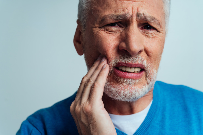 Patient touching cheek due to denture sores