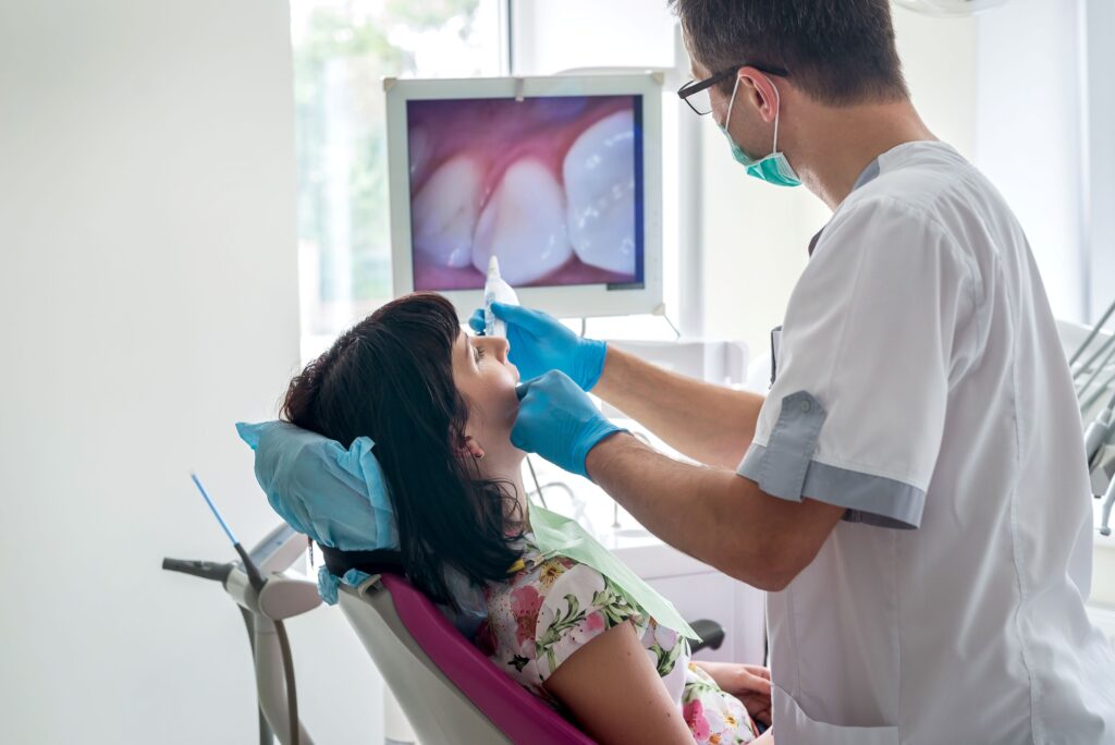 Dentist examining woman's mouth with intraoral camera
