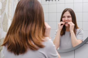 a patient smiling while holding their Invisalign aligner
